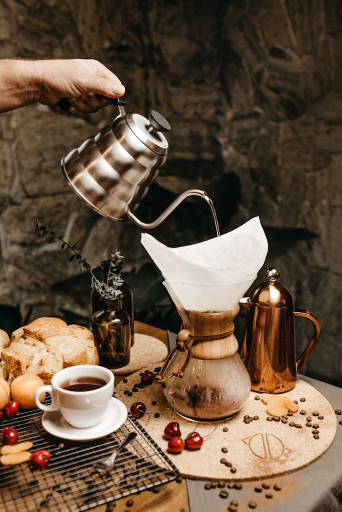 pexels-photo-2878712 Hand pouring coffee into a Chemex surrounded by fresh cherries and breakfast items indoors.
