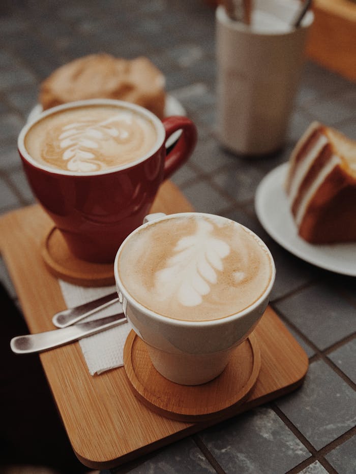 pexels-photo-3020919 Delicious latte art accompanied by a slice of cake on a cafe table.