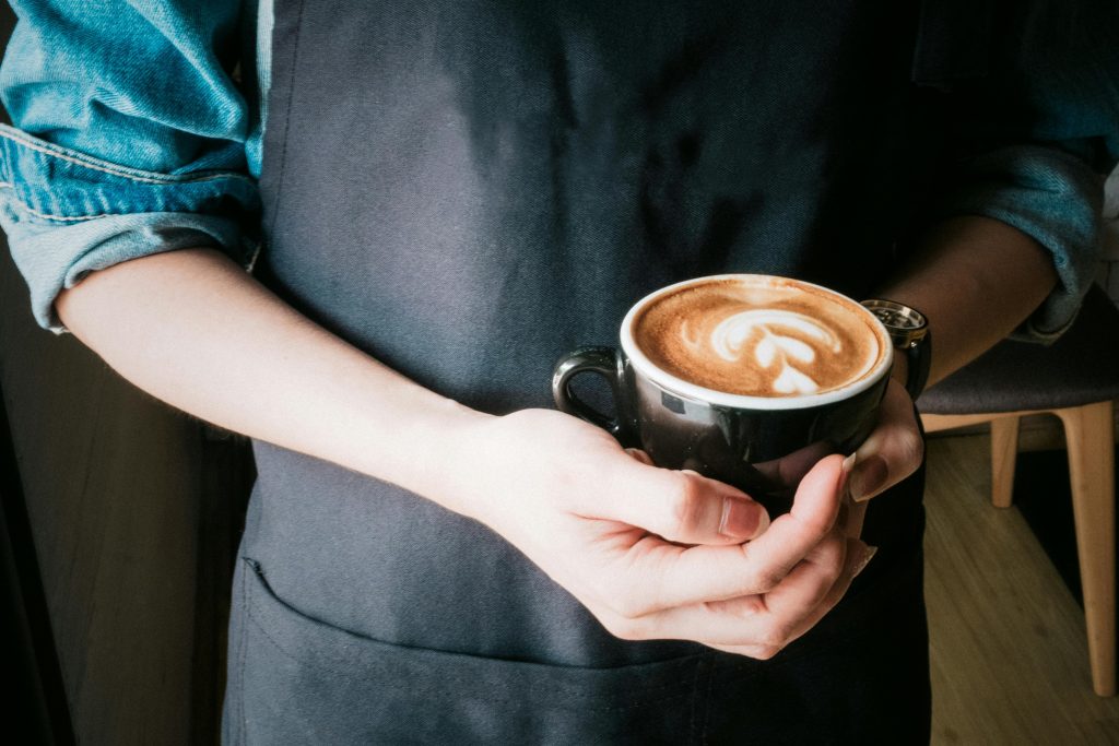 pexels-photo-373639-373639 A barista holds a coffee cup with beautiful latte art in a cozy café setting.